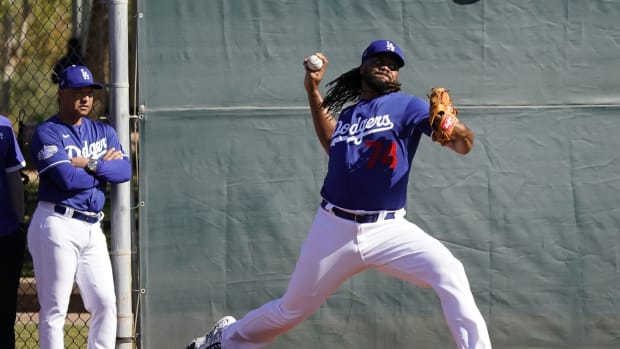Feb 14, 2020; Glendale, Arizona, USA; Los Angeles Dodgers relief pitcher Kenley Jansen (74) throws in the bullpen as manager Dave Roberts (left) looks on during spring training. Mandatory Credit: Rick Scuteri-USA TODAY Sports